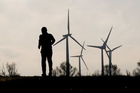 Jogger im Gegenlicht vor Windrädern: Bis zum 32-Prozent-Ziel ist es ein weiter Weg. Um es zu erreichen, will die EU die Zusammenarbeit der Mitgliedsstaaten verbessern.