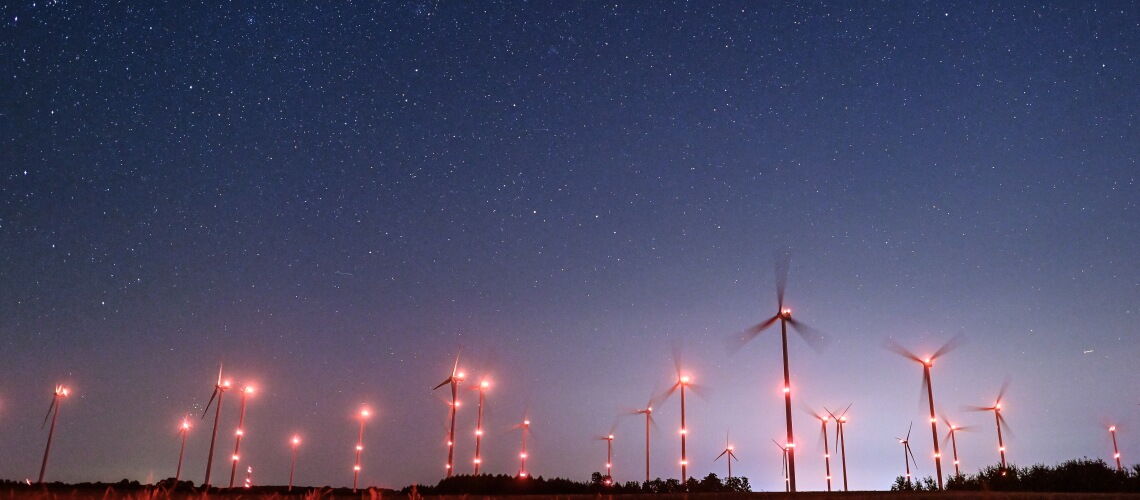 Blinkende Windräder unter nächtlichem Sternenhimmel: Künftig sollen die Anlagen nur noch dann aufleuchten, wenn sich ein Flugzeug nähert.