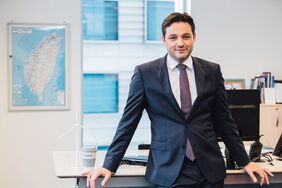 Matthias Bausenwein, Ørsted-Manager in Taiwan in seinem Büro in Taipeh. Hinter ihm hängt eine Karte des Inselstaats. Die ersten Offshore-Windräder drehen sich bereits vor der Küste.