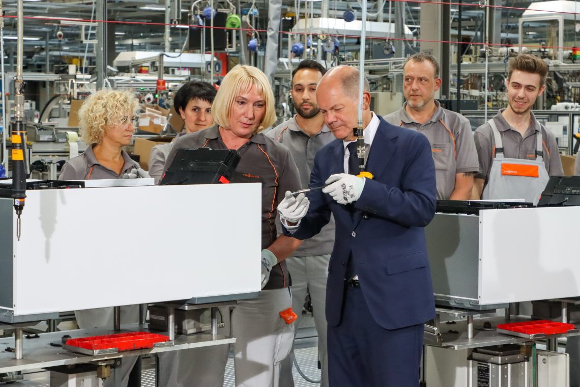 Kanzler Olaf Scholz schraubt eine Wärmepumpe von Viessmann bei einem Werksbesuch zusammen: Wärmepumpen sind einer Studie zufolge auch für mäßig gut sanierte Altbauten geeignet.