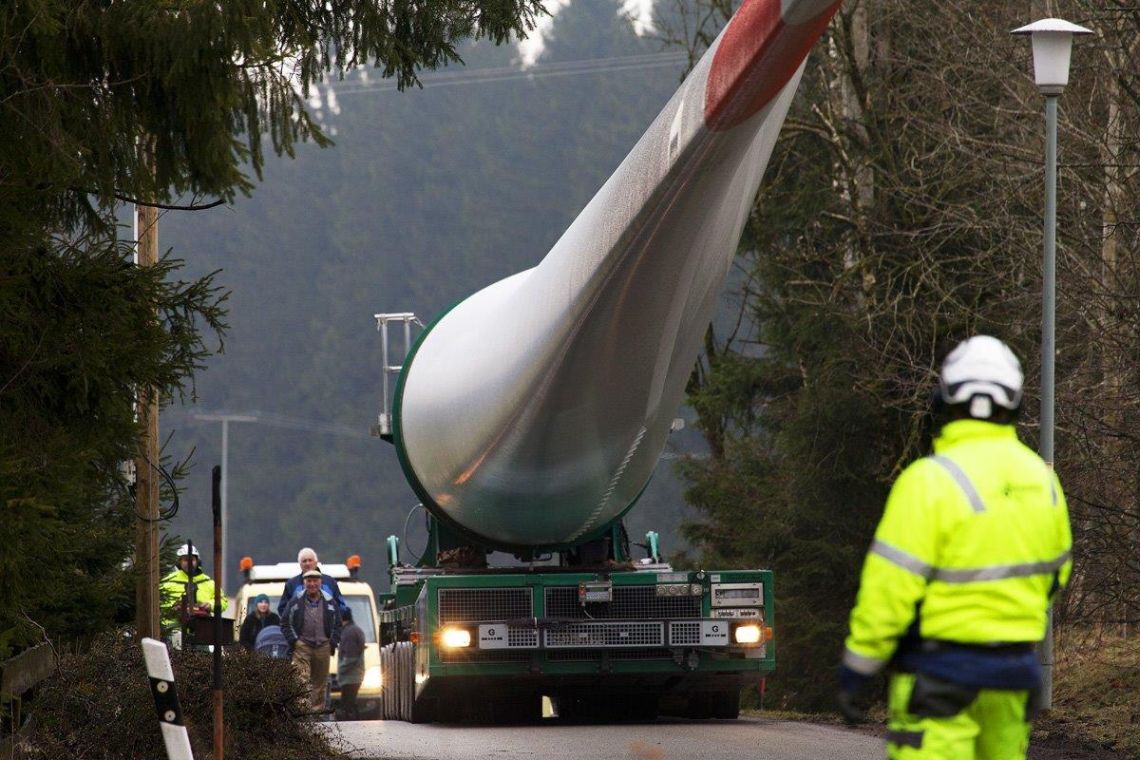 Transport eines Rotorblatts durch eine besonders enge Passage: Zahlreiche Zuschauer sind gekommen, um zuzusehen, wie das große Blatt die Strecke meistert.