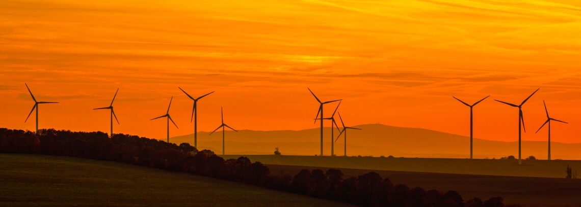 Windräder im Sonnenuntergang: Alte Anlagen, die keine EEG-Förderung mehr erhalten, können oft mithilfe eines PPA weiterbetrieben werden.
