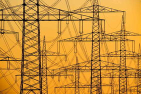 Strommasten und Stromleitungen bei Sonnenaufgang: Durch ein neues Temperatur-Messverfahren, das sogenannte Freileitungsmonitoring, sollen die Leitungen mehr Strom transportieren können.