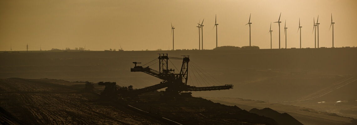 Vergangenheit trifft Zukunft: Am Rande des Tagebaus Garzweiler stehen Windräder. Durch den vorgezogenen Kohleausstieg wird Platz für Ökostrom im Stromnetz frei.
