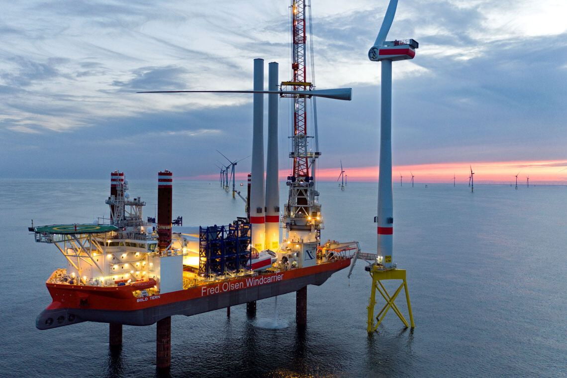 Vom Errichterschiff „Bold Tern“ aus installieren Techniker die Rotorblätter eines Offshore-Windrads.